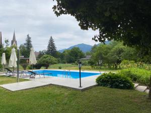 a swimming pool with tables and umbrellas and a church at Hotel Kürschner in Kötschach