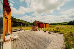 a wooden deck with a cabin in a field at Nowoczesne Domki na Łące - Sauna & Balia & Jacuzzi - PolanaGlamp in Nieżyn