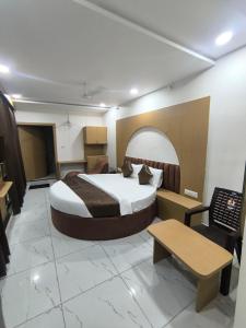 a hotel room with a large bed and a table at Hotel RD in Kadi +8 photos
