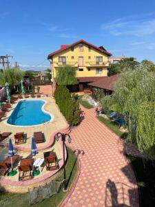 a resort with a pool and chairs and a building at Pensiunea Bianca in Murighiol