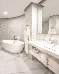 a white bathroom with a tub and a sink at Yacht Hotel in Vlorë