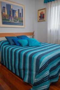 a bed with blue pillows in a bedroom at Apartamento Aurora cerca de Laredo y Santoña y Piscina Comunitaria in Bádames +41 photos