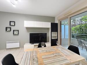 Un comedor con una mesa con sillas y un televisor. en Cosy nid, terrasse & 2 parkings, en Antibes