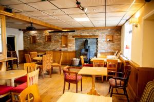 a restaurant with tables and chairs and a brick wall at The Cresselly Inn in Mountain Ash