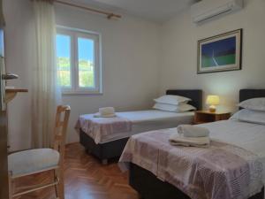 a hotel room with two beds and a window at APARTMENTS JELENA SUPETAR - three apartments - a small house with a private yard - two-room apartment with a sea view - three-room apartment with garden and barbecue - free parking in Supetar