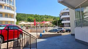a red car parked in a parking lot next to a building at Comfortable Studio in Sunset Resort Complex, Kosharitsa in Kosharitsa