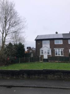 a brick house with a solar roof on a yard at Northern homestay between High Peak & Manchester in Hadfield