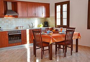 una cucina con tavolo con 4 sedie e una cucina con piano cottura di Eden Villa ad Alinda