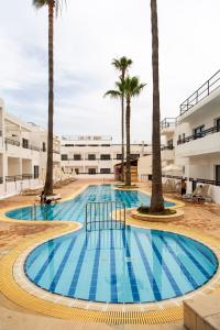 a swimming pool with palm trees in front of a building at Summer's Hotel Apartments in Ayia Napa