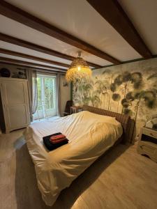 una camera da letto con un grande letto bianco con un lampadario di Marais Inn, maison typique avec piscine et jardin arboré, 10 kms Niort a Sansais Altre 22 foto