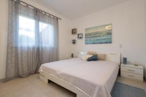 a white bedroom with a bed and a window at Apartmani Simona Tribunj in Tribunj