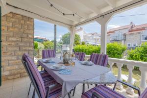 a table with purple chairs sitting on a porch at Apartmani Simona Tribunj in Tribunj