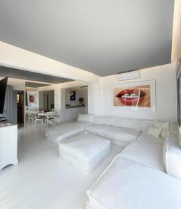 a white living room with white couches and a tv at CASA GEKKO - MYKONOS by ROOMERS HOTELS in Mýkonos City