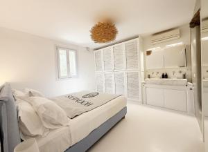 a white bedroom with a bed and a sink at CASA GEKKO - MYKONOS by ROOMERS HOTELS in Mýkonos City +24 photos