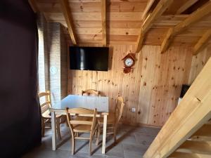 a dining room with a table and a clock on a wall at Kukaj Apartments in Gusinje