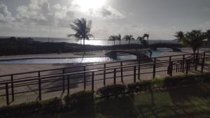a pool with a bridge and palm trees and the ocean at Golden Dunas 123B in Extremóz