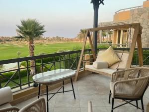 3BR Duplex with Private Rooftop in Ein Bay في العين السخنة: شرفة مع أرجوحة وكراسي وملعب جولف