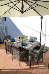 a dining table with chairs and an umbrella at Casa Alma Lusa - Olhão center - 2 bedrooms in Olhão