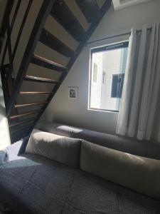 een kamer met een bed, een raam en een bank bij Loft Lampião in Campina Grande