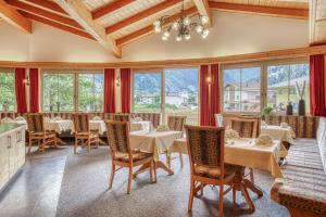 a restaurant with tables and chairs and windows at Hotel Jägerhof Ötz in Oetz