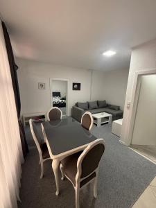 Una sala de estar con una mesa y sillas y un sofá. en Renoviran i novo namješten Apartman, en Velika Kladuša