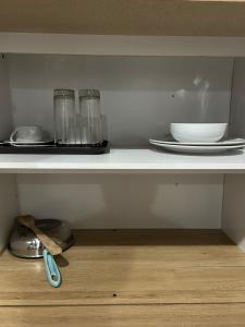 a shelf with two glasses and plates and a bowl at Devata 68 Private Room VIP in Uluwatu