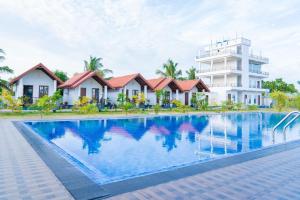 a hotel swimming pool in front of a building at US Cabanas in Nilaveli