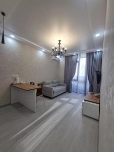 ein Wohnzimmer mit einer Couch und einem Kronleuchter in der Unterkunft СДАМ студию с видом на море, Alley Palace, Alley of Heroes in Batumi in Itʼkhvisi
