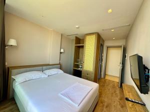 a bedroom with a white bed and a television at Green Condo Hotel Palase in Palasë