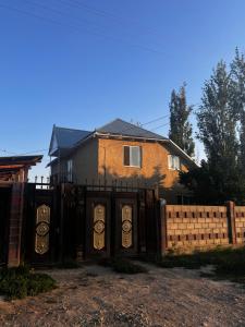 a house with a gate in front of a fence at ERLAN Guest House in Jangy-Talap