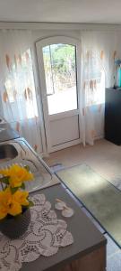a kitchen with a door and a table with a vase of flowers at Apartman Asja in Utjeha