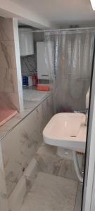 a white bathroom with a sink and a shower at Apartman Asja in Utjeha +4 photos
