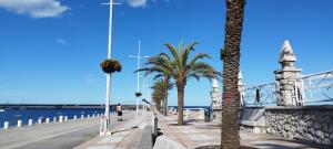 a woman walking down a sidewalk next to a pier with palm trees at Castro-urdiales Apartamento 3 minutos de la playa in Castro-Urdiales