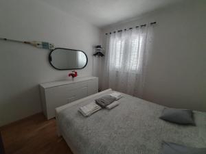 a white bedroom with a bed and a mirror at Anja in Vir
