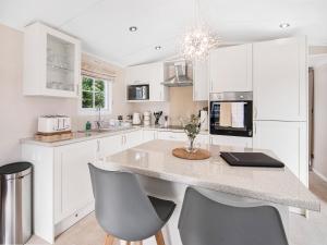 a kitchen with white cabinets and a island with chairs at European Lodge - Uk40848 in Scarborough +12 photos