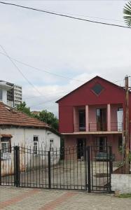 una casa roja detrás de una valla negra en Amirans guest house, en Kobuleti