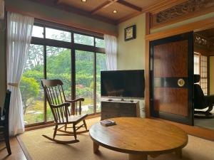 un soggiorno con tavolo, TV e sedia di 日本庭園と文化体験の宿深見屋 一棟貸し送迎付き6名様まで追加宿泊料金なし a Hakusan