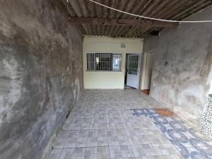 an empty room with a stone wall and a tile floor at Casa 2 minutos a pé da Praia de INDAIÁ in Bertioga