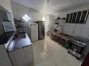 a kitchen with a refrigerator freezer and a counter top at Casa 2 minutos a pé da Praia de INDAIÁ in Bertioga +8 photos