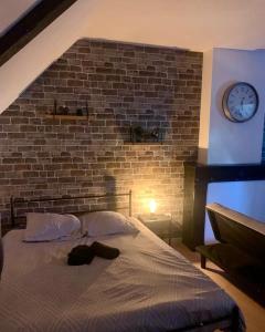 a bed in a room with a brick wall and a clock at Cosy Loft New-Yorkais in Guingamp