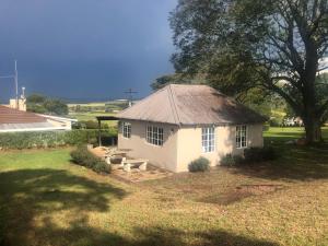 a small white house with a picnic table in a yard at The Pastures Eston Farm Stay in Mid Illovo +23 photos