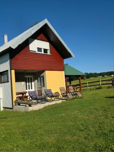 a red and yellow house with chairs and a yard at Mountain house Savin Kuk in Žabljak