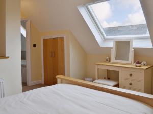 a bedroom with a skylight and a bed and a desk at Dairy Cottage in Matfield