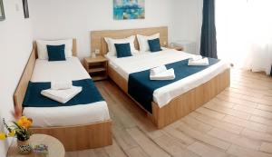 two beds in a room with blue and white pillows at Vila Lorena in Mangalia