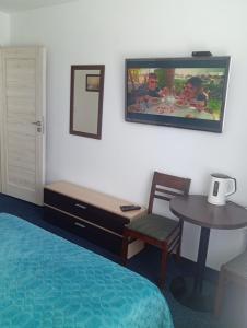 een hotelkamer met een bed, een tafel en een tv bij Dom Hermana in Mrzeżyno