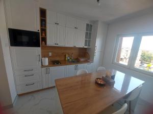 a kitchen with white cabinets and a wooden table at Apartman Lenka Bijeljina in Bijeljina