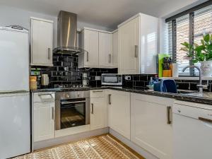 a kitchen with white cabinets and a stove top oven at Cozy Lodges in Barton upon Humber +7 photos