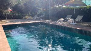 a swimming pool with chairs and an umbrella at Cabaña La Pura Vida Yunquera in Yunquera