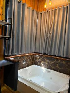 a bath tub in a bathroom with a shower curtain at Hospedaria Cambará in Cambará +34 photos