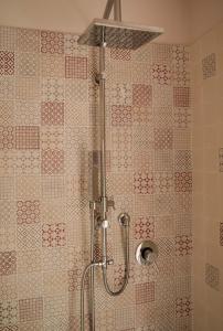 a shower in a bathroom with red and white tiles at La stamberga nel bosco in Asciano Pisano